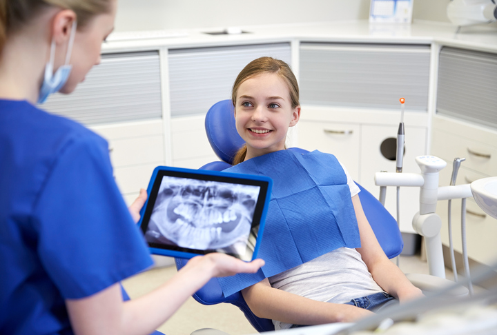 dentist with x-ray on tablet pc and patient girl dentist with x-ray on tablet pc and patient girl