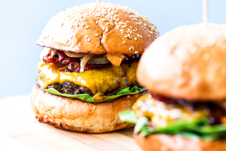 Freshly flame grilled bacon cheese burgers in row Freshly flame grilled bacon cheese burgers in row