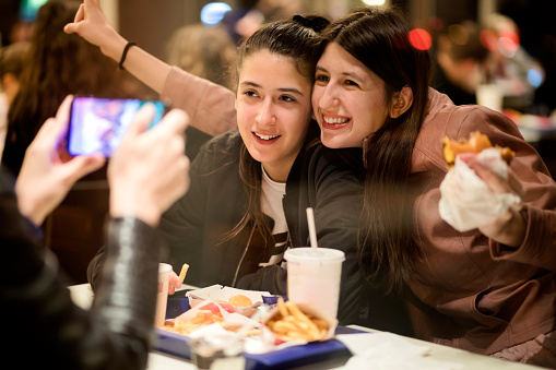 Mother with her teenage daughters enjoying in fast food restaurant
