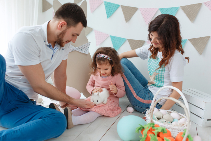 Happy easter family playing with rabbit in decorated studio interior