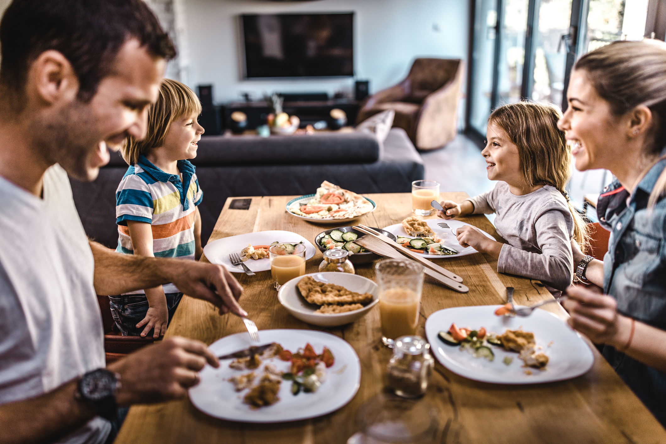 Young happy family talking while having lunch at dining table.