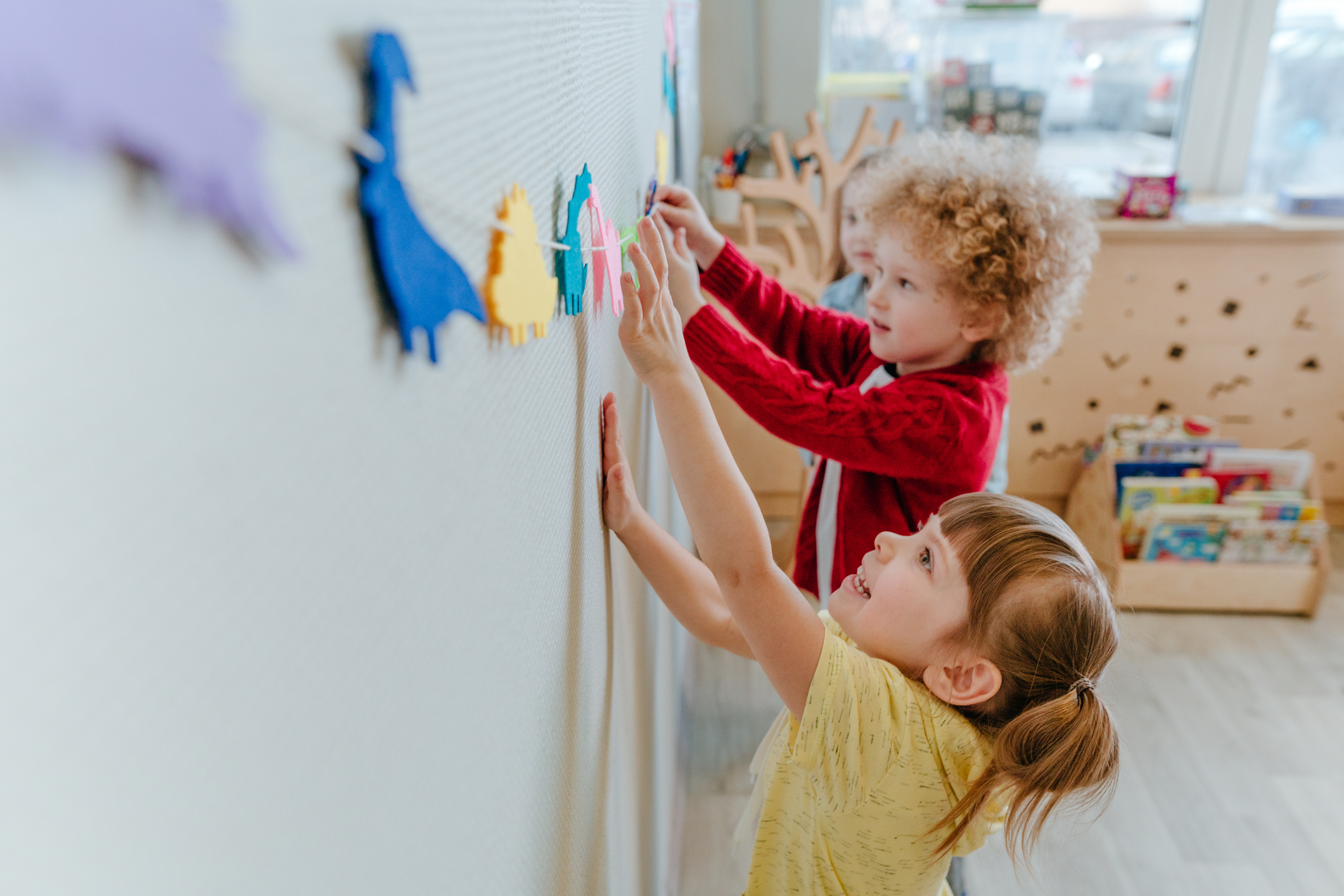 Preschool students playing in kindergarten with color dinosaur figures